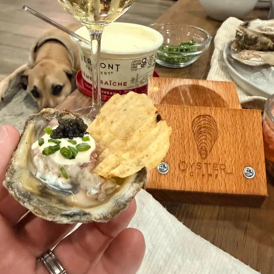 A dressed oyster held over the OysterClamp at a dinner table